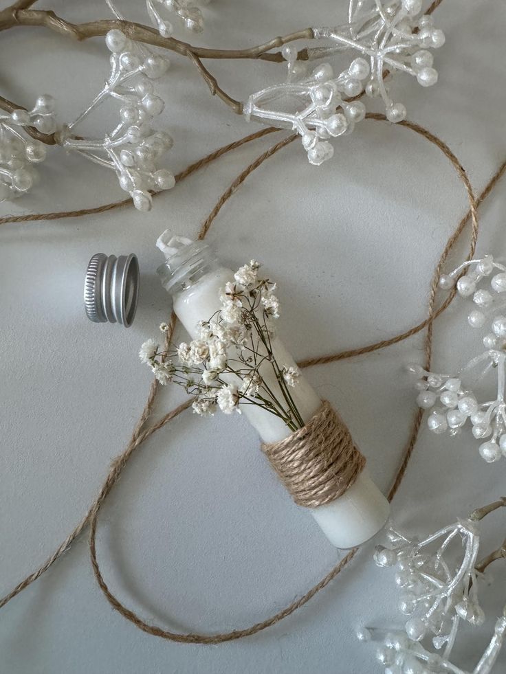 some flowers are in a glass bottle on a tablecloth with twine and beads