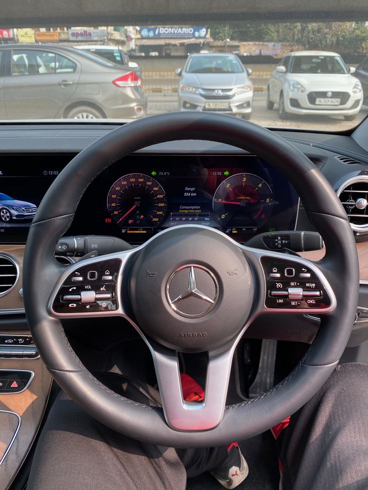 the interior of a car with dashboard, steering wheel and other vehicles in the background