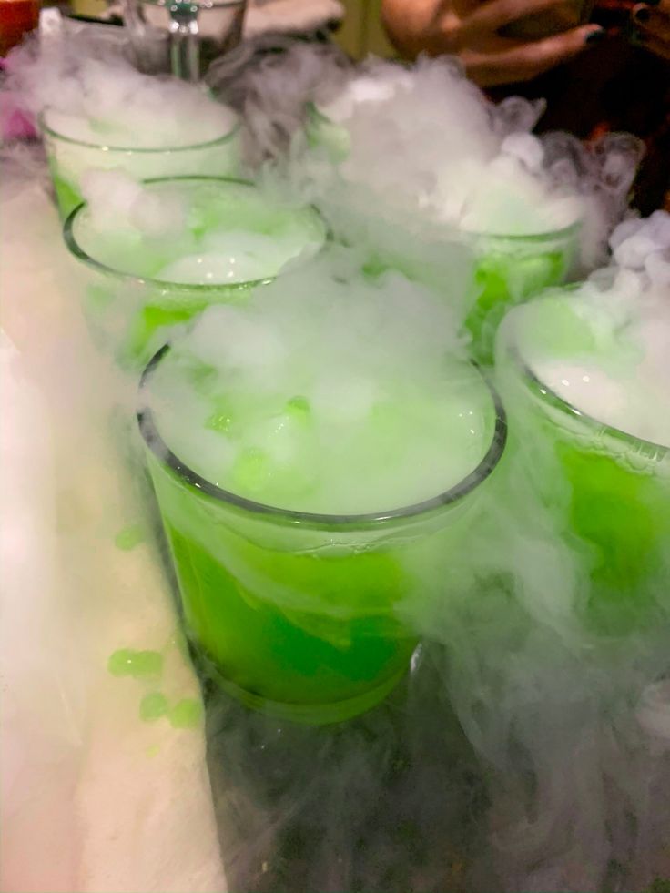 several glasses filled with liquid sitting on top of a counter covered in ice and steam