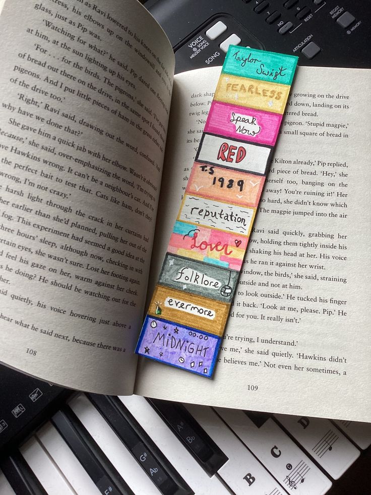 an open book sitting on top of a table next to piano keys and a keyboard