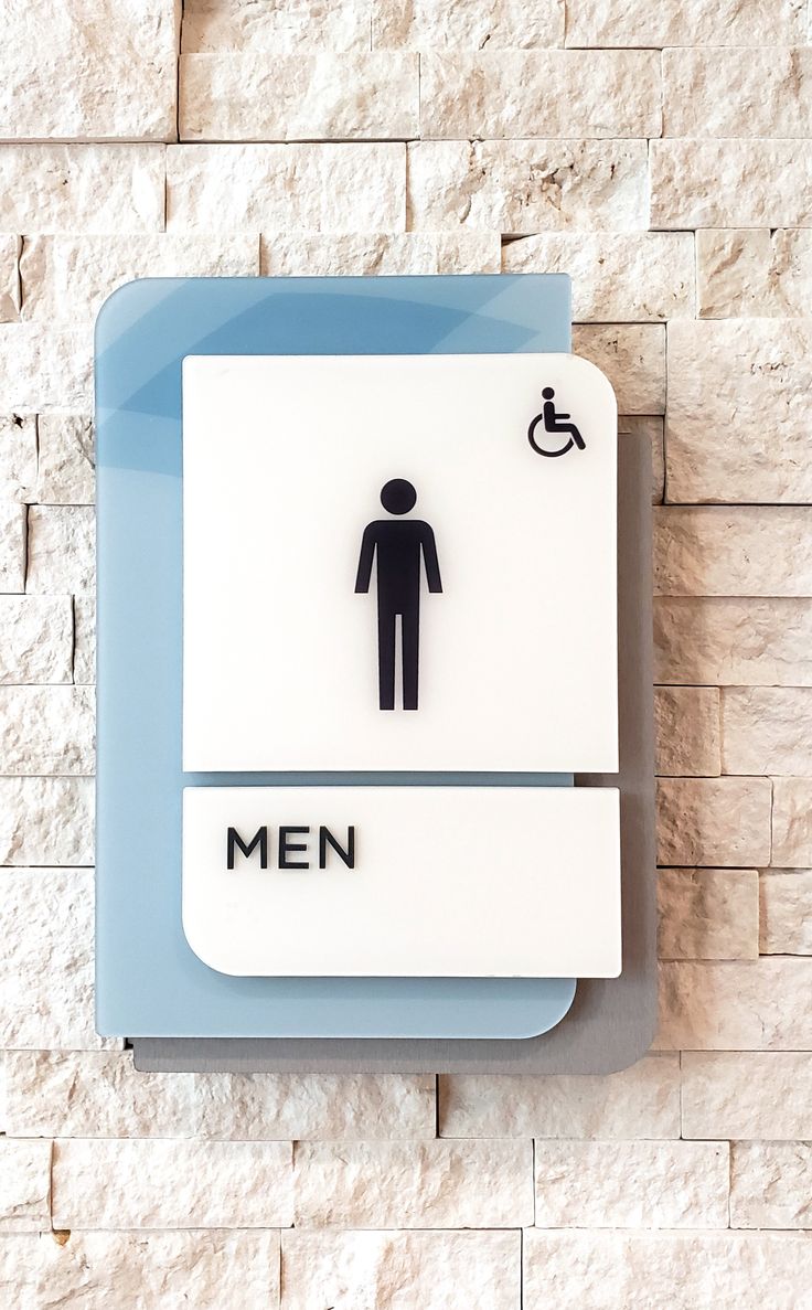 a blue and white bathroom sign with a man in a wheel chair on it's side