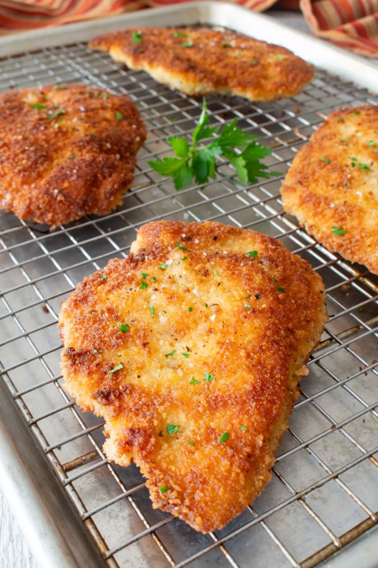 four pieces of chicken on a cooling rack with parsley sprinkled on top