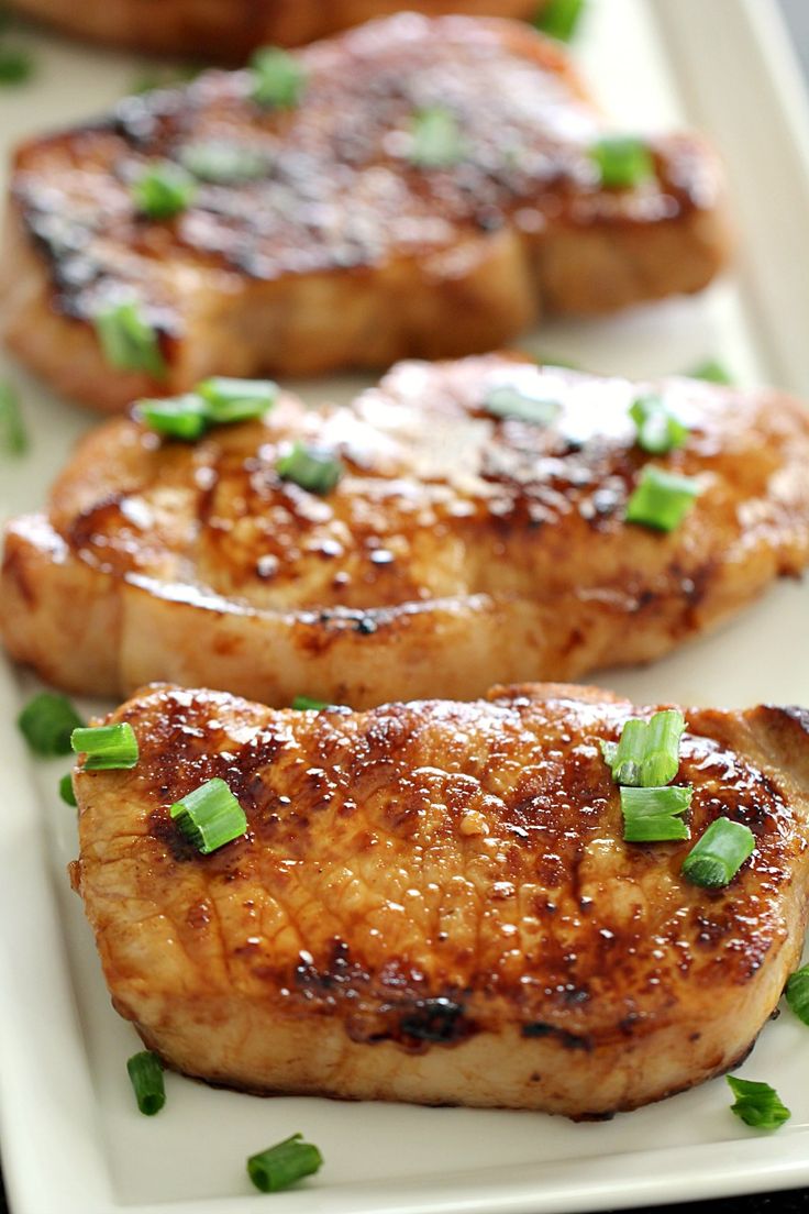 marinated pork chops on a white plate with green onions