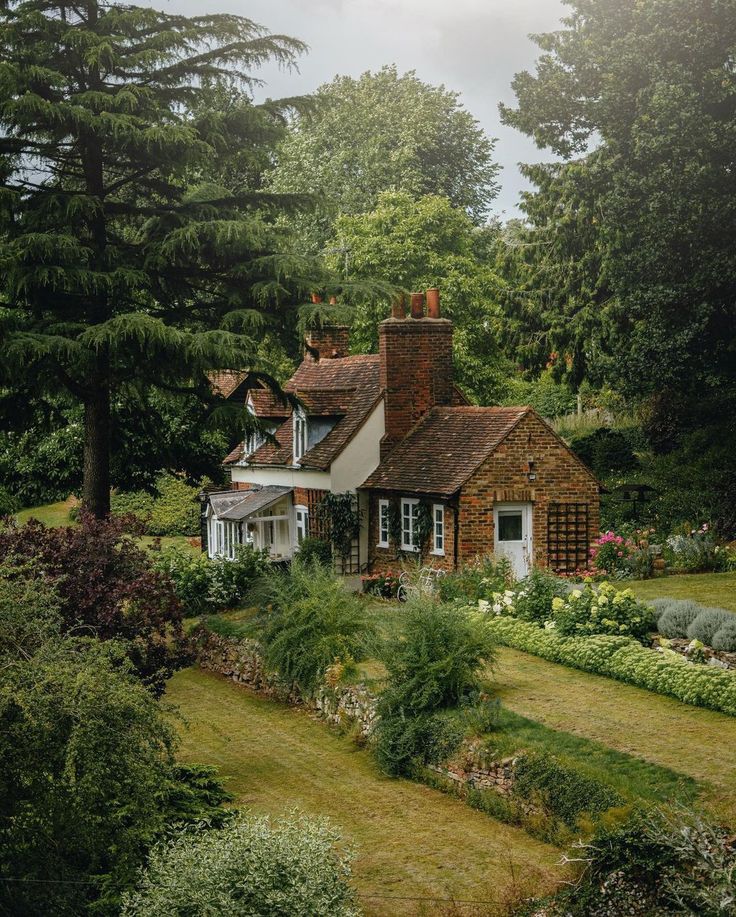 a house in the middle of a lush green field with lots of trees and bushes