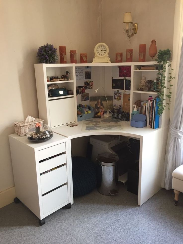 a corner desk with books and other items on it in a room that has carpeted flooring