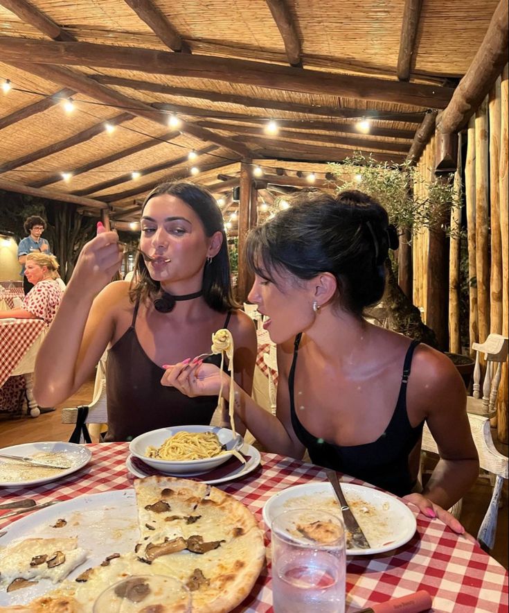 two women sitting at a table with plates of food