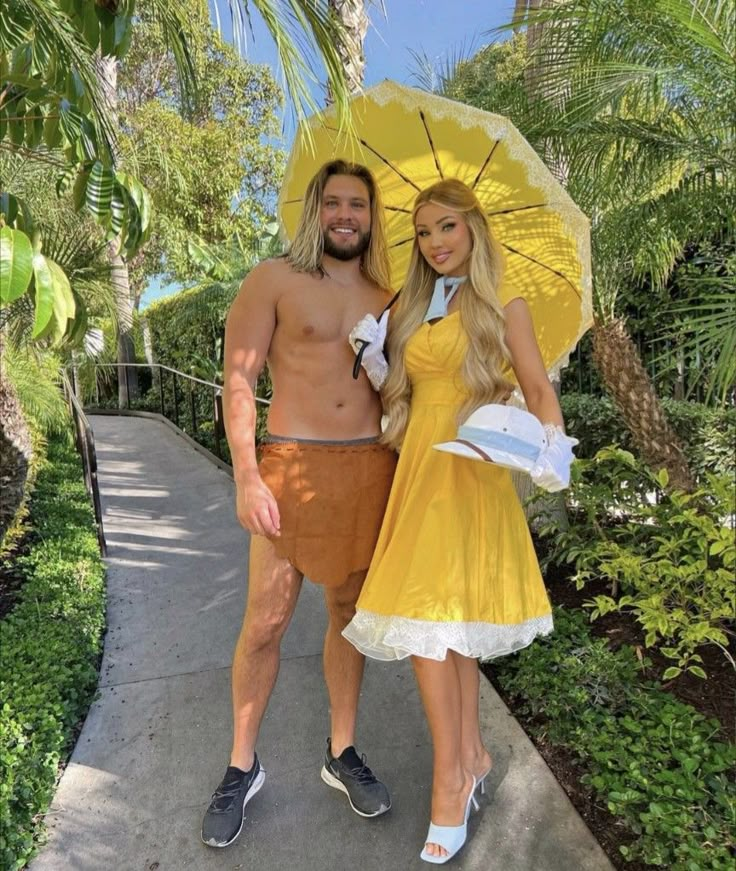 a man and woman dressed up in costumes posing for the camera with an umbrella over their heads