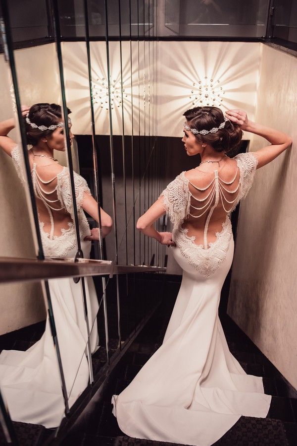 a woman standing in front of a mirror with her back to the camera and wearing a wedding dress