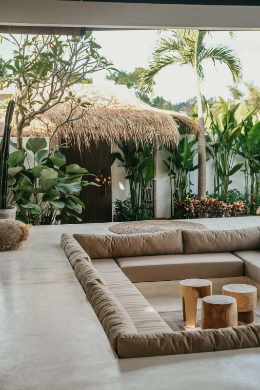 a living room filled with lots of furniture next to plants and trees in the background