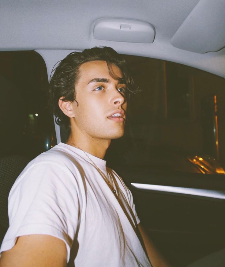 a young man sitting in the back seat of a car with his head turned to the side