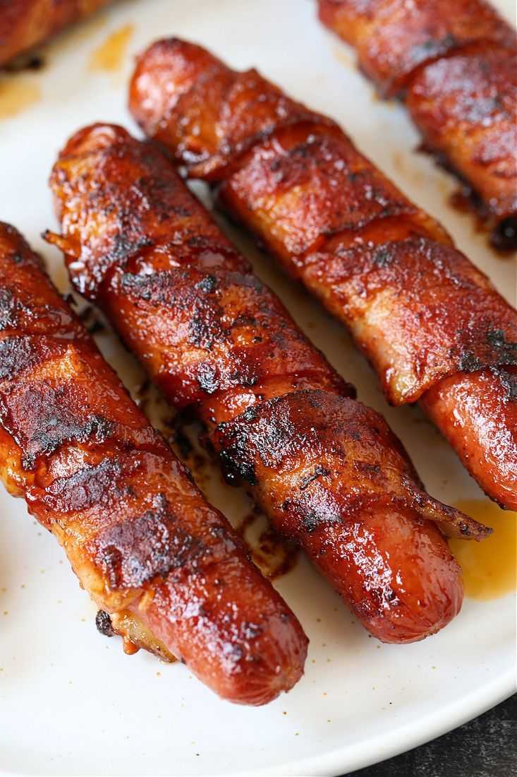 several sausages on a white plate with mustard