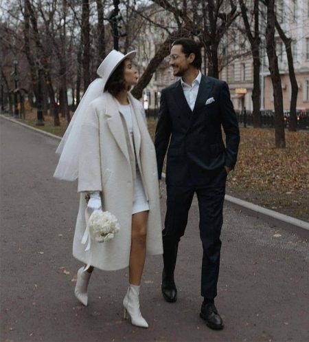 a man and woman dressed in white walking down the street with their hands behind each other