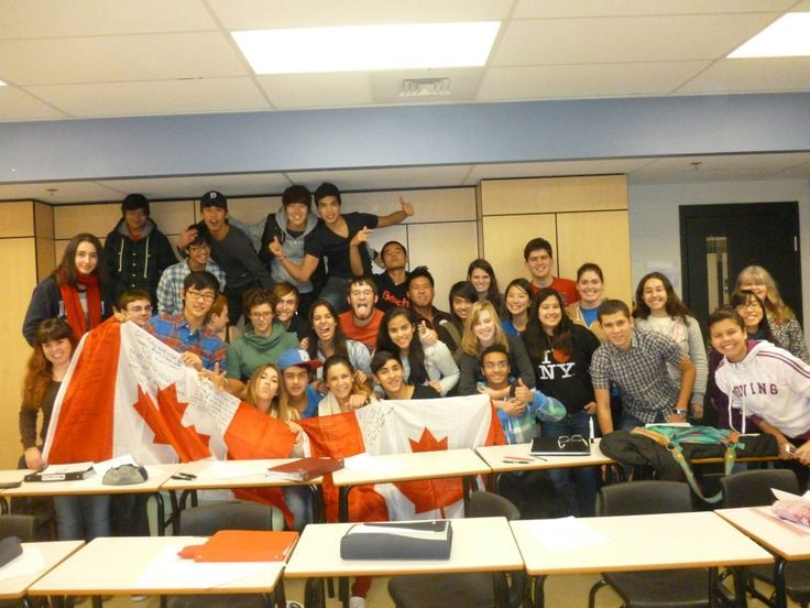 a group of people posing for a photo in front of desks with canadian flags