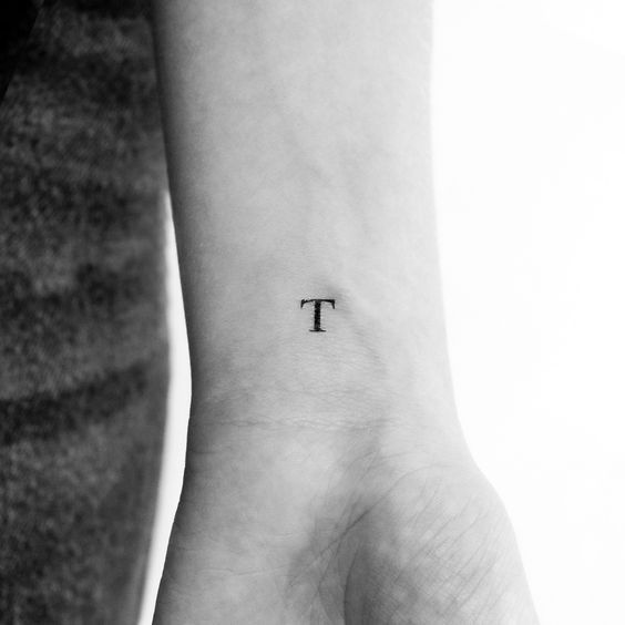 a person with a small tattoo on their wrist that has the letter t in it