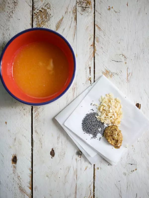 a bowl of soup next to two plates with food on them and an orange sauce in the middle