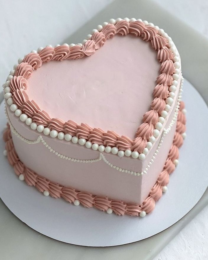 a heart shaped cake with pink icing on a plate