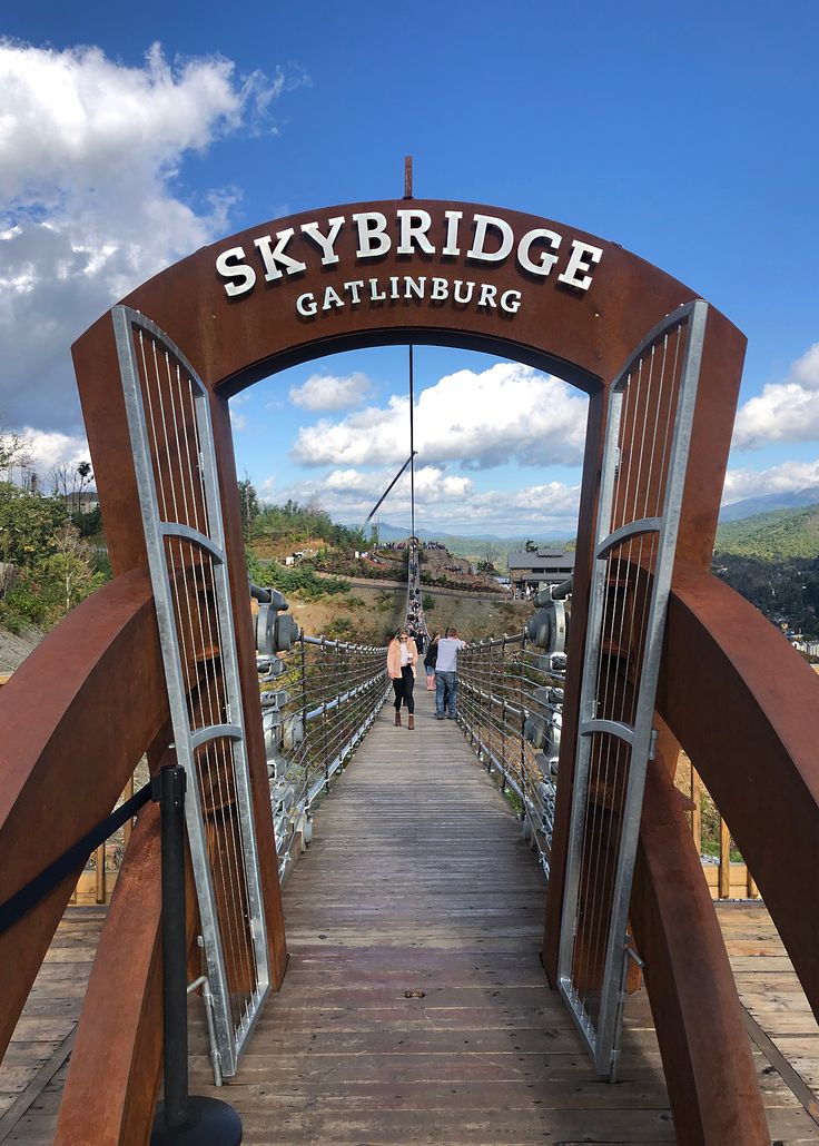 people are walking across a bridge that has a skybridge sign above it on top