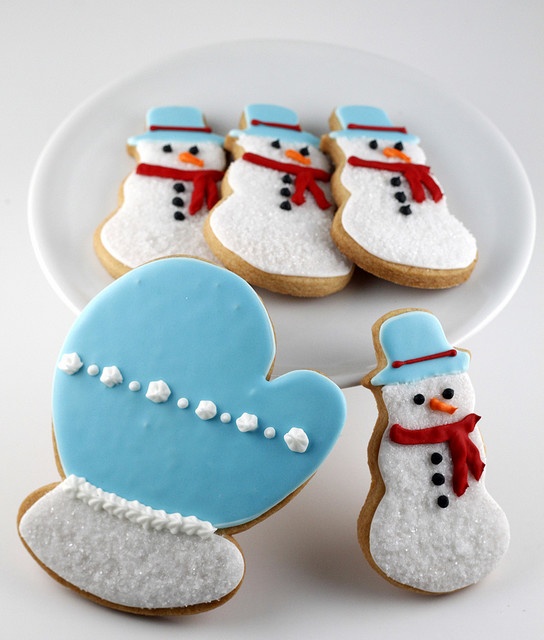 decorated cookies with frosting and icing are on a plate next to snowmen