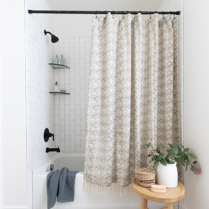 a bathroom with a bathtub, shower curtain and towel rack on the counter next to it