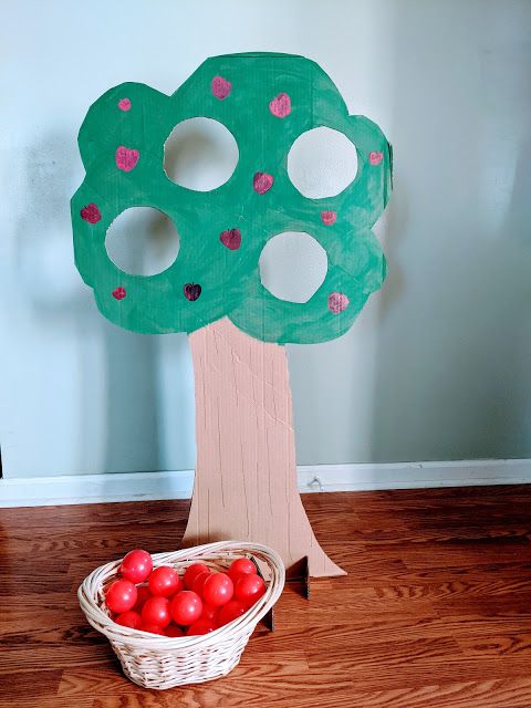 a paper plate apple tree with apples in a basket on the floor next to it