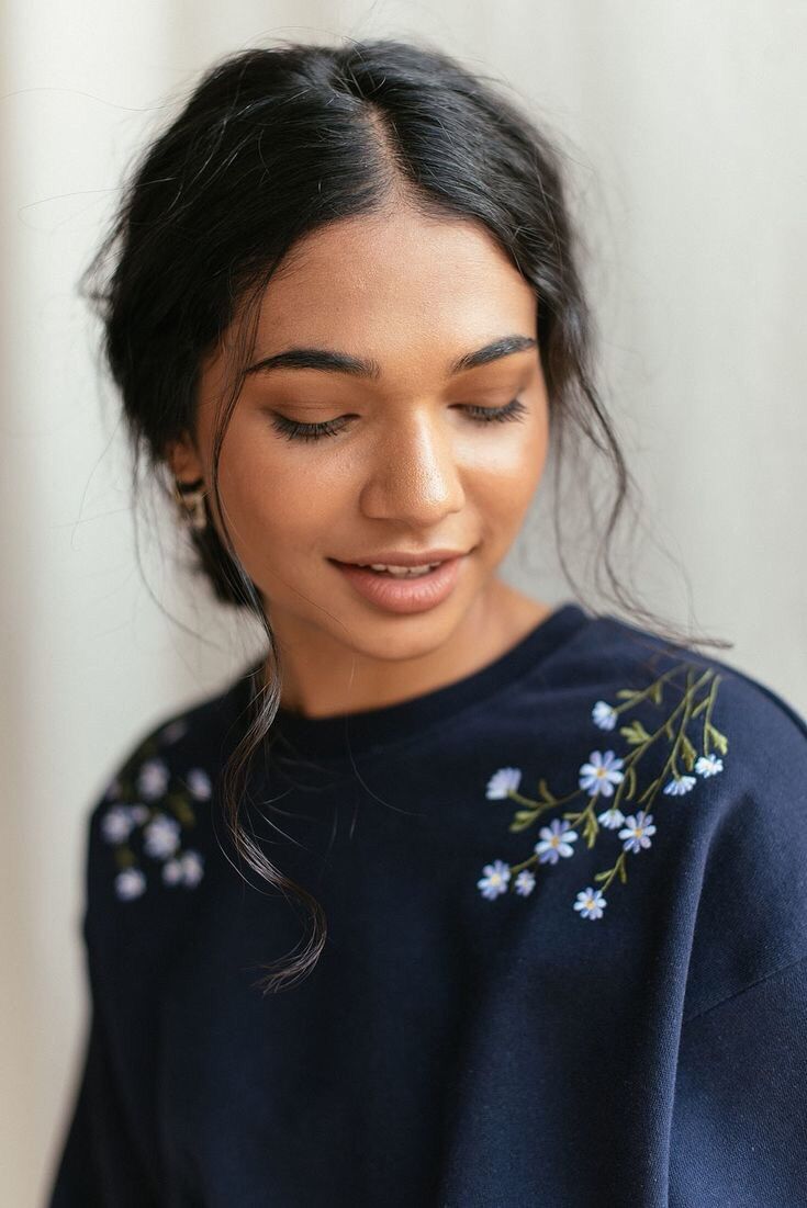 a woman with her eyes closed wearing a blue sweater and holding a cell phone in her hand