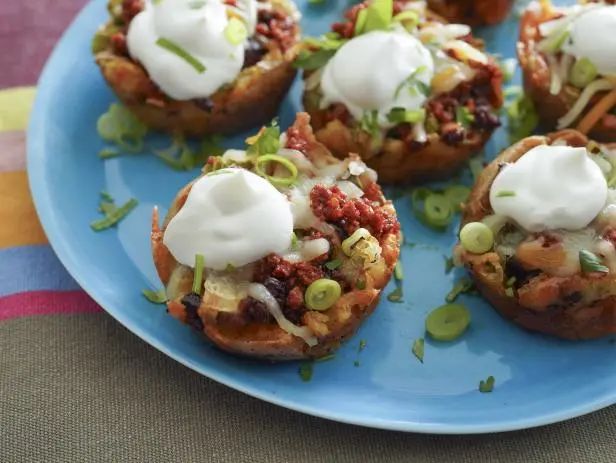 a blue plate topped with mini taco shells covered in sour cream and toppings