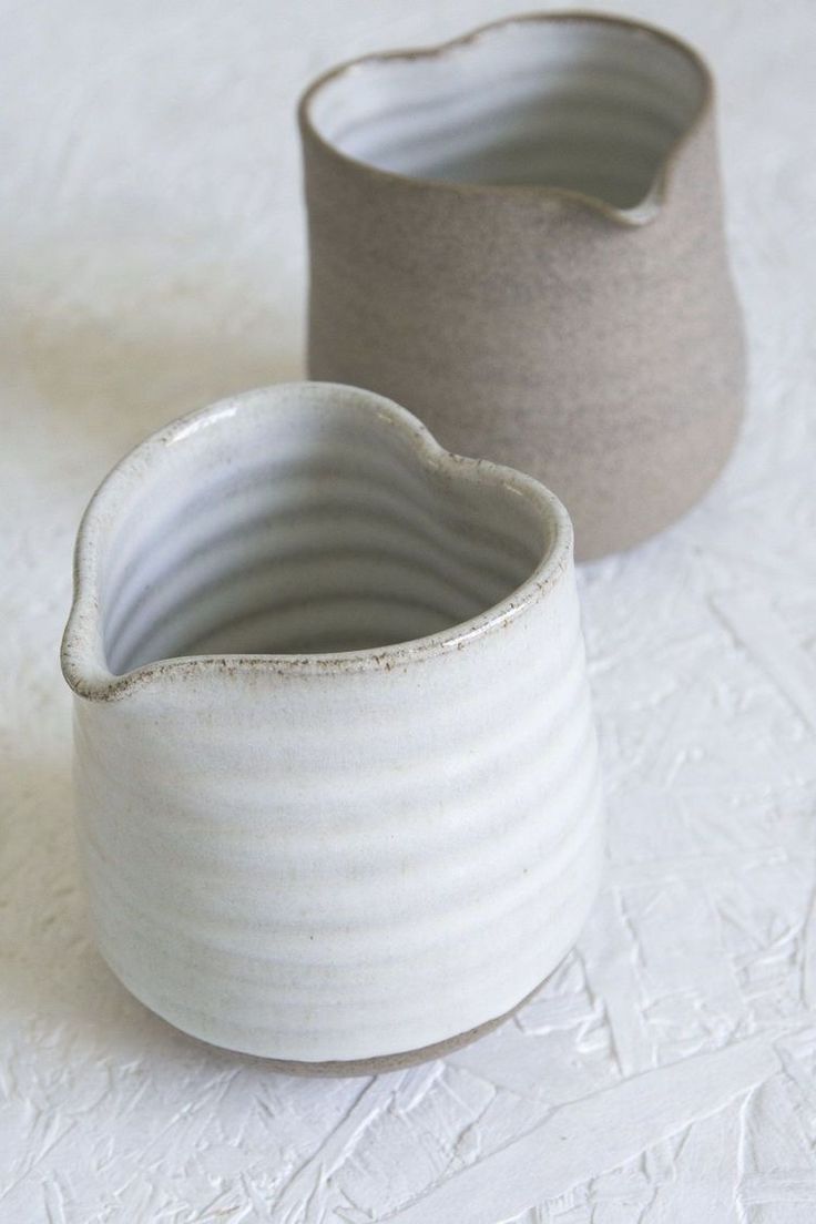 two white vases sitting next to each other on a table