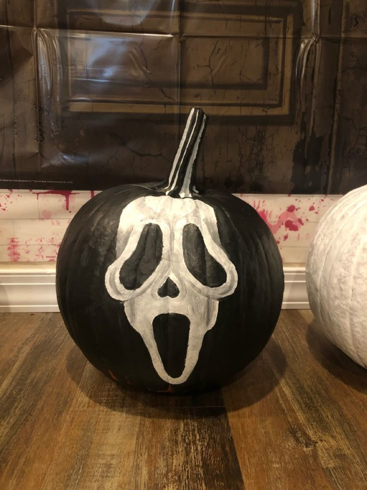 a black and white pumpkin with a skeleton face painted on it sitting in front of a wall