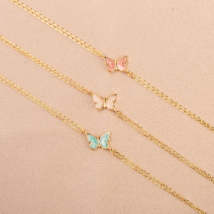 Our 14K Gold Butterfly Bracelet is a dainty and enchanting piece, perfect for adding a touch of whimsy and color to your jewelry collection. Each bracelet features intricately crafted butterfly charms, detailed with vibrant enamel in shades of blue, pink, or white. These charms, measuring 9mm x 6mm, are set against the backdrop of lustrous 14K gold, available in your choice of Gold, Rose Gold, or White Gold. The adjustable length of 6.5" to 7.75" ensures that the bracelet can comfortably fit a v Blue Enamel Bracelet Jewelry, Enamel Jewelry As Gift For Her, Enamel Jewelry As A Gift For Her, Rose Gold Adjustable Jewelry With Butterfly Charm, Adjustable Rose Gold Jewelry With Butterfly Charm, Adjustable Jewelry With Butterfly Charm For Friendship, Adjustable Butterfly Charm Jewelry For Friendship, Elegant Enamel Jewelry With Delicate Chain, Fine Gold Enamel Jewelry