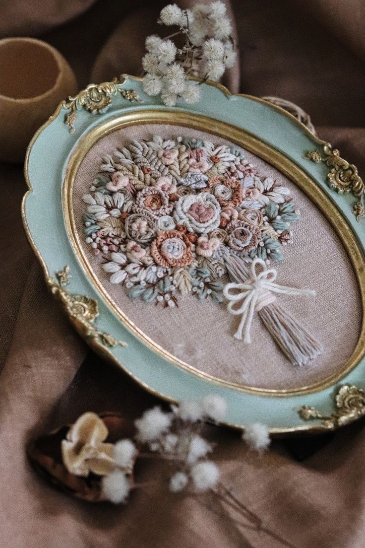 an ornately decorated tray with flowers and tassels on it next to a cup