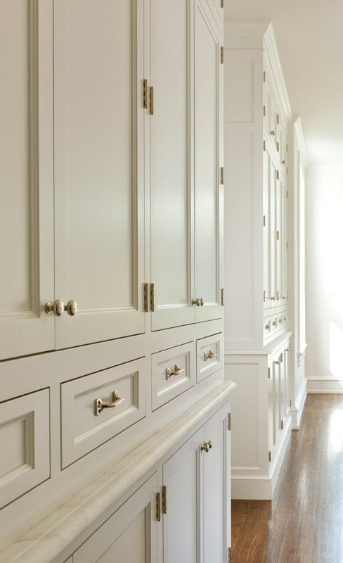 an empty kitchen with white cabinets and wood floors