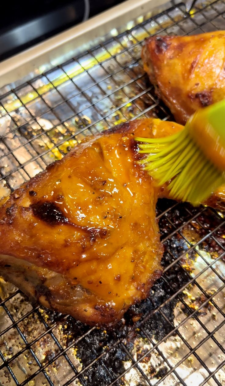 two pieces of meat on a grill with a spatula being used to brush them off