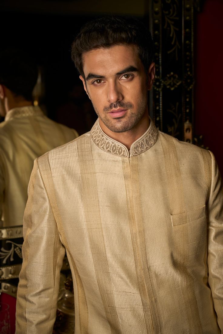 This set features stitch lines in gold thread in a stripe pattern. The collar has delicate dori embroidery. It is paired with a matching cotton silk kurta and straight pants. Complimenting stole and footwear is also available. DELIVERY TIMEPlease allow 8-12 weeks for your outfit to arrive. FABRIC DETAILSSherwani - Raw Silk, Kurta - Cotton Silk, Trouser - Cotton Silk, Dupatta - Cotton Tissue Organza Professional cleaning only. Unstitched Bandhgala With Gold Embroidery For Eid, Ceremonial Cotton Silk Bandhgala For Festivals, Elegant Cotton Silk Kurta With Cutdana, Ceremonial Cotton Silk Bandhgala With Zari Work, Traditional Cotton Silk Bandhgala For Ceremonial Occasions, Cotton Silk Bandhgala For Ceremonial Eid, Ceremonial Cotton Silk Sherwani With Resham Embroidery, Gold Cotton Silk Churidar With Straight Kurta, Gold Cotton Silk Churidar With Traditional Drape