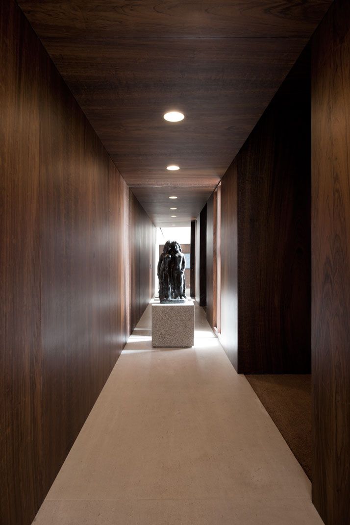 the hallway is lined with wooden walls and flooring, along with a sculpture in the center