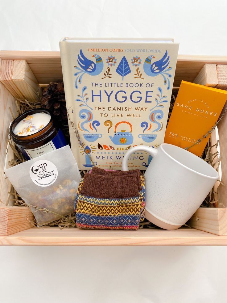 a wooden box filled with lots of different items next to a coffee cup and book