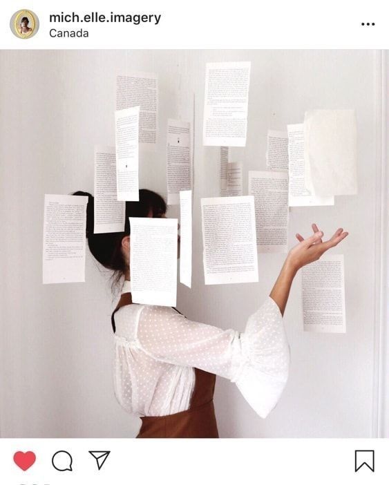 a woman is holding up some papers on the wall with her hands in front of her face