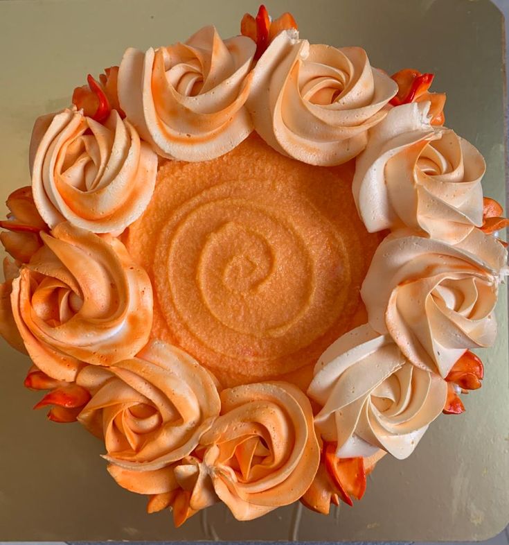 an orange cake with white frosting and flowers