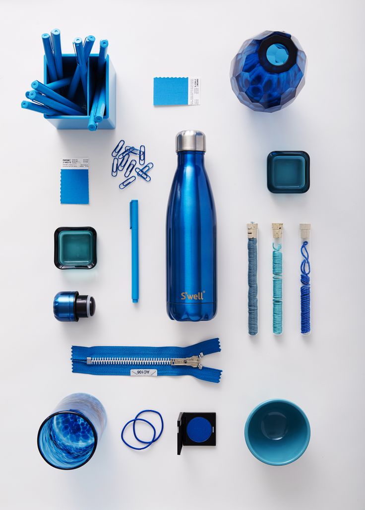 the contents of a blue water bottle laid out on a white surface, including toothbrushes and other items