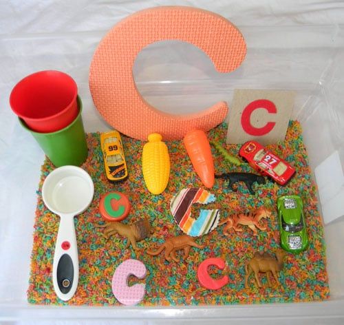 there is a plastic container with toys and letters in it on the tablecloths