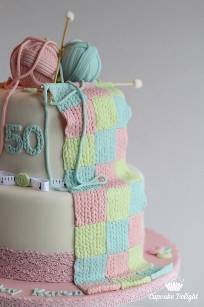 a cake decorated with yarn and knitting needles