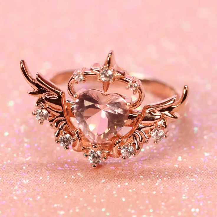 Overcome with love, the happiness and warmth can make anyone’s heart soar! The Camilla Ring - Sunset Pink features a heart-shaped, pastel pink synthetic centre stone with a halo of shining stars and magnificent angel wings at either side. The ring is crafted from sterling silver .925 plated in 14KT rose gold. Please note that with proper care, plated jewelry may need to be replated every 1-2 years. This order will take around 1-2+ weeks to package and process plus additional shipping time. Engagement Rings Pink, Pink Wedding Ring, Cute Promise Rings, Pink Wedding Rings, Sunset Pink, Cute Engagement Rings, S Heart, Magical Jewelry, Girl Jewelry