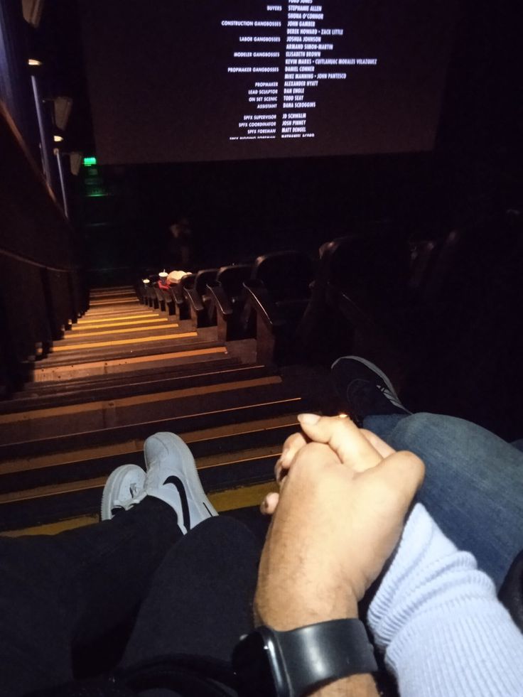 two people sitting in front of a screen watching something on the wall at night time