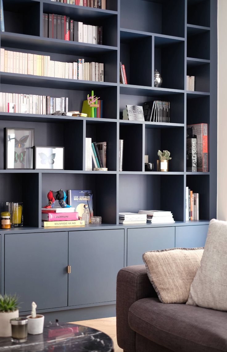 a living room filled with lots of blue bookshelves