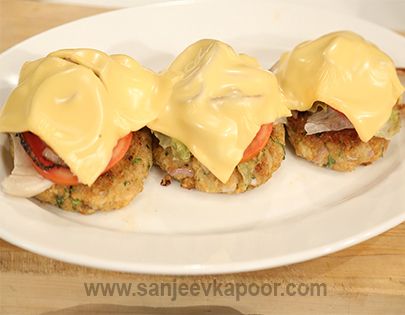 two crab cakes covered in mayonnaise on a white plate