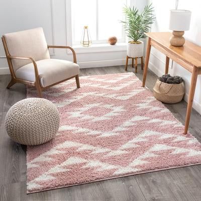 a living room with white furniture and pink rugs on the floor, along with two chairs