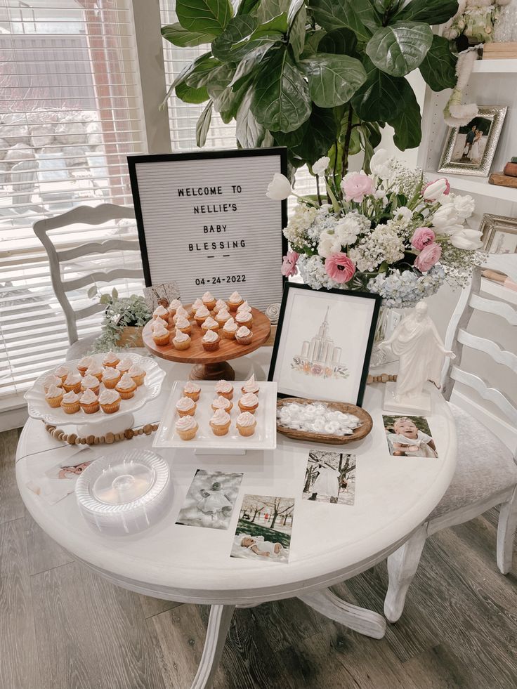 a white table topped with lots of pastries next to a vase filled with flowers