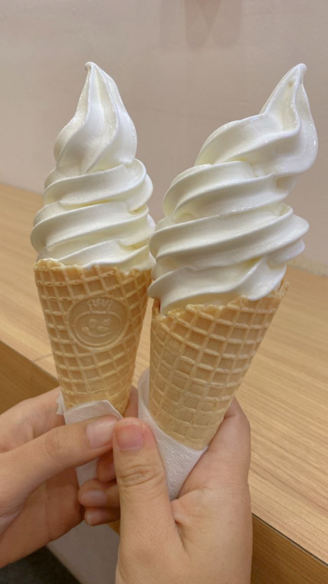 two ice cream cones are being held up