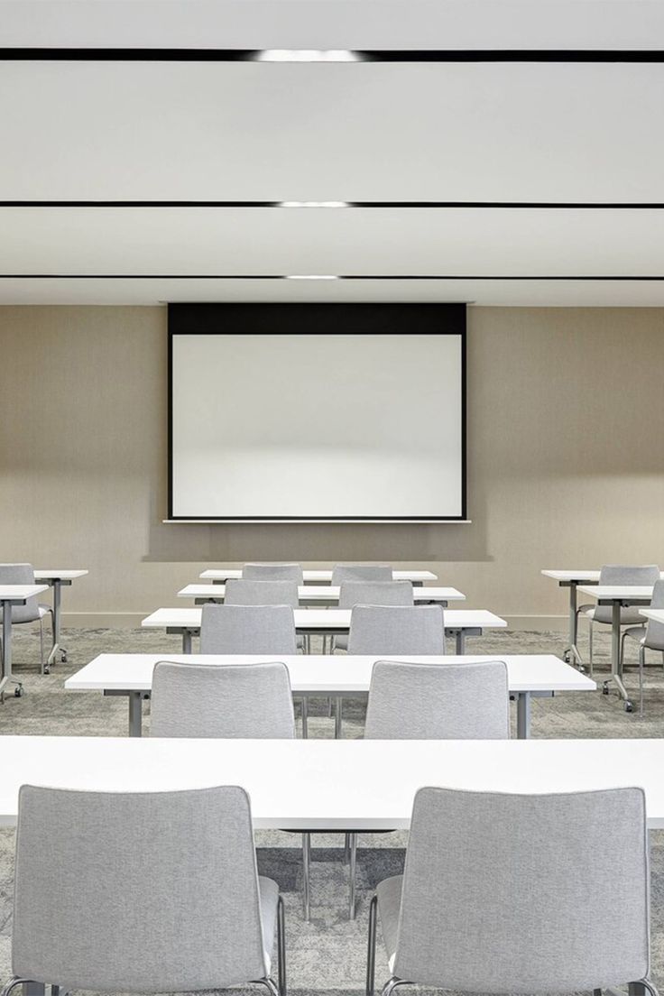 an empty conference room with chairs and a projector screen in the middle of it