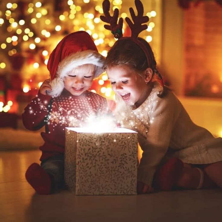 two young children are playing with a small box that is lit up and surrounded by christmas lights