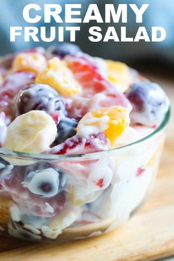 a bowl filled with fruit salad on top of a wooden cutting board